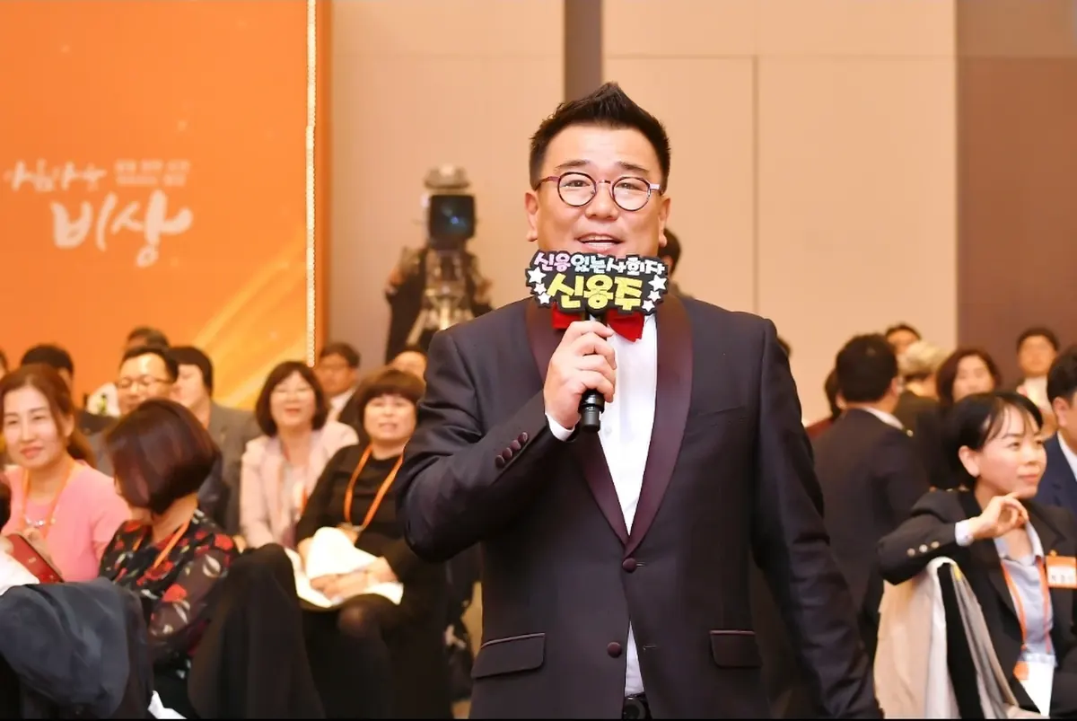객석 앞에서 마이크를 들고 행사를 진행하는 MC 신용주